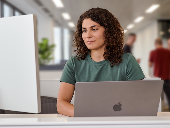 En Apple-medarbetare använder en MacBook och Studio Display på ett kontor.