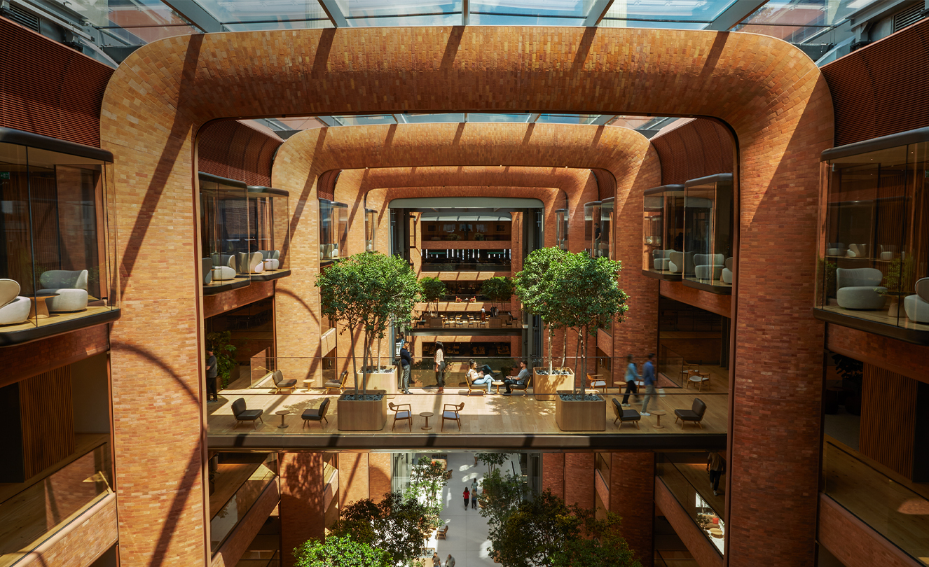 Batterseas atrium i fem våningar med solen som strömmar in genom glastaket och lyser upp medarbetare nedanför.