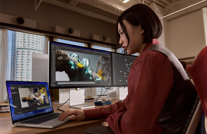 Une personne travaillant dans un bureau avec un MacBook Pro connecté à un Studio Display XDR