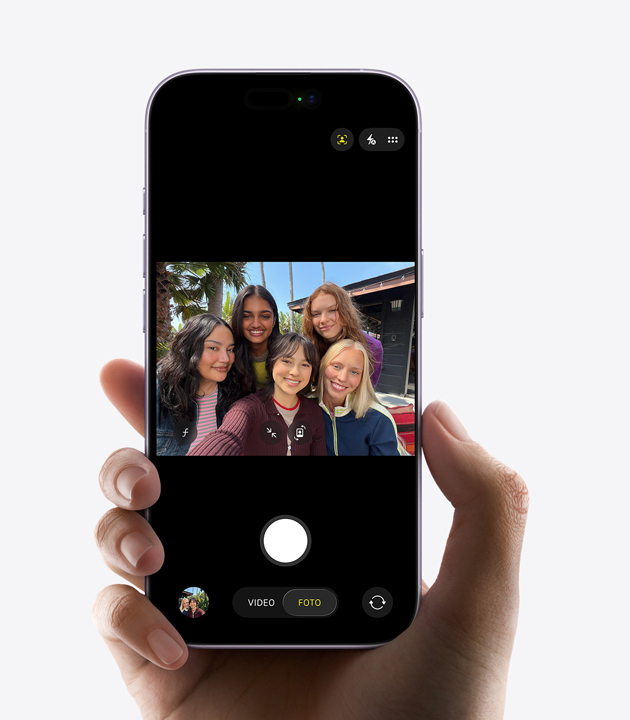 Parte frontal de un iPhone mientras captura una selfie de cinco personas con la cámara frontal Center Stage