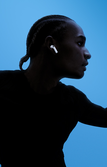 AirPods 5 ‑kuulokkeita käyttävä henkilö, kädet levällään, värikäs tausta