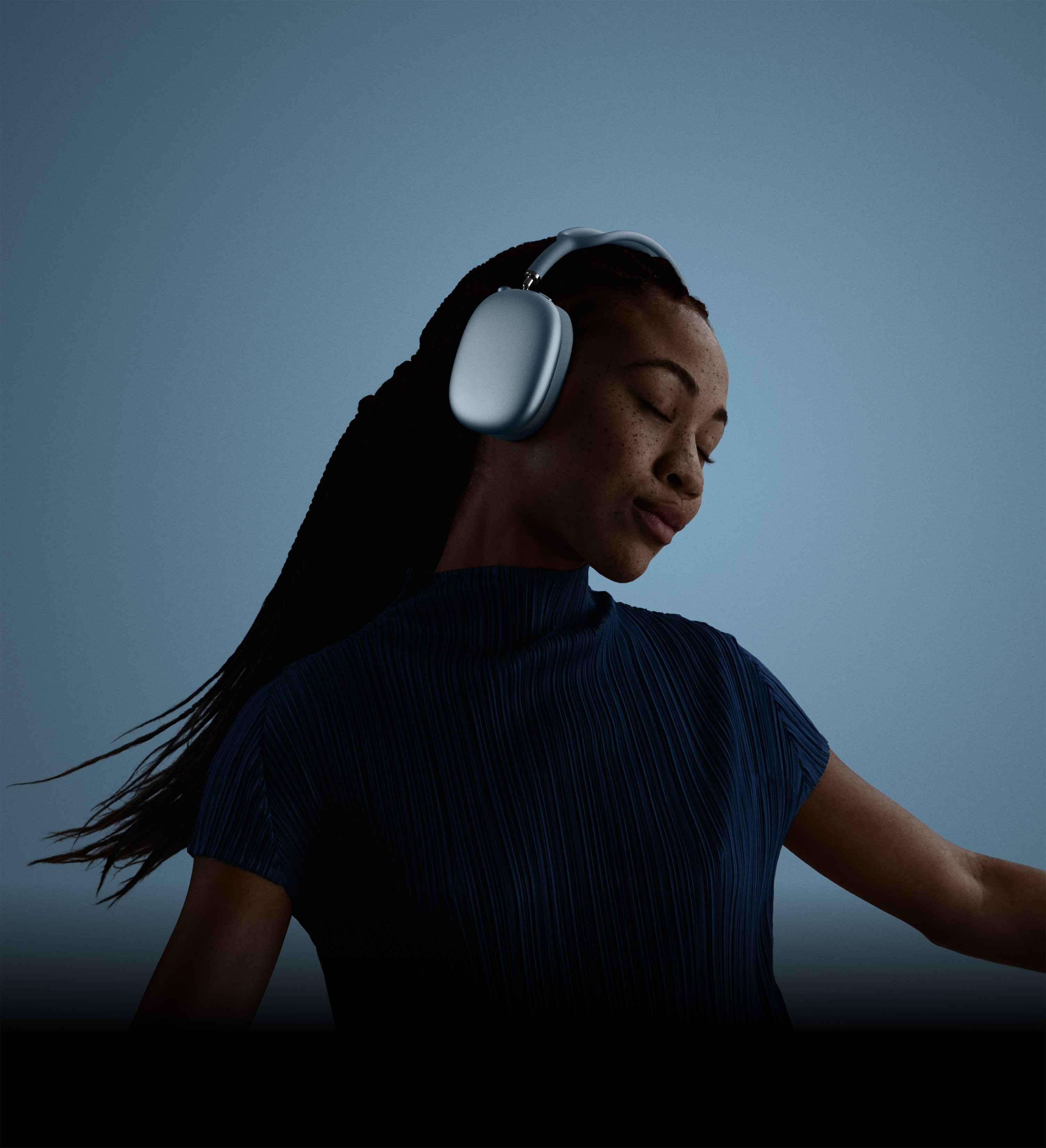 Užsimerkusio ir galvą pakreipusio žmogaus su mėlynos spalvos ausinėmis „AirPods Max 2“ profilis.