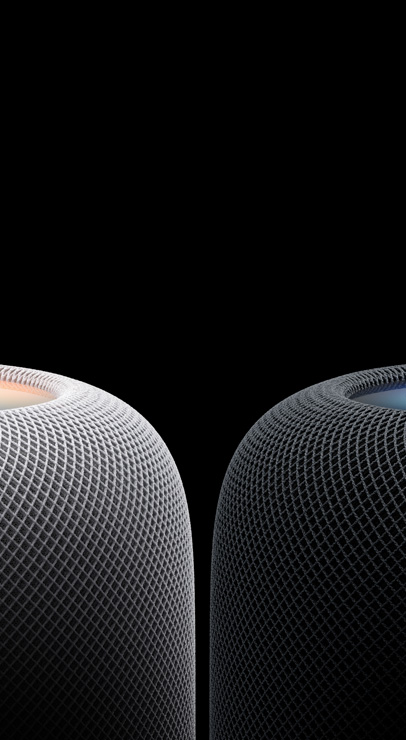 Two HomePod speakers, positioned side by side, cylindrical, rounded edges, glowing touch surface on top, white colour and midnight colour