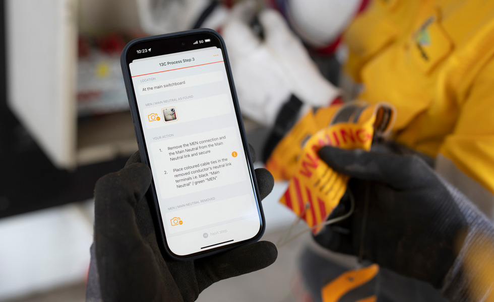 Bàn tay cầm iPhone hiển thị hướng dẫn thực hiện kiểm tra tủ điện, với dòng chữ Quy Trình 13C Bước 3 trên màn hình