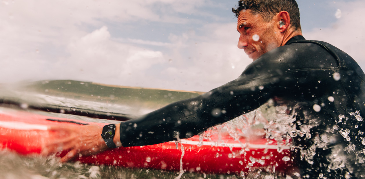 Un uomo che fa surf con un Apple Watch al polso.