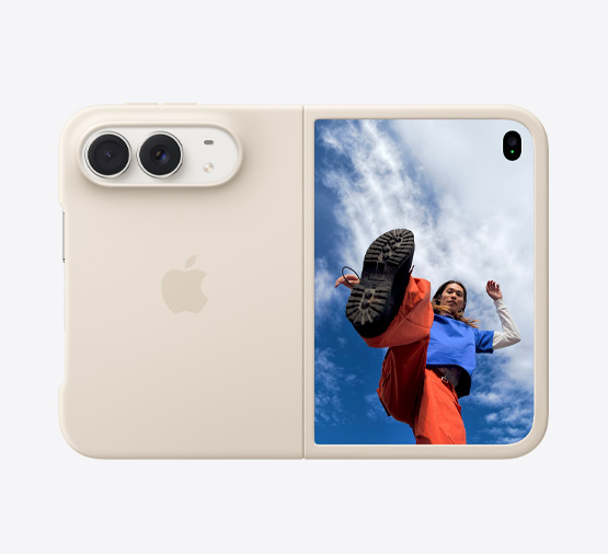 Teljesen kinyitott csillagfehér iPhone Duo homokszín szilikontokban, fekvő tájolásban, külső nézetben, a hátoldal bal felső sarkában a Dual Fusion kamerákkal, a tok a hátoldalt és a külső kijelző szélét fedi le, a jobb oldalon lévő külső kijelzőn egy emberről készült fotó, a háttérben felhős kék égbolttal.