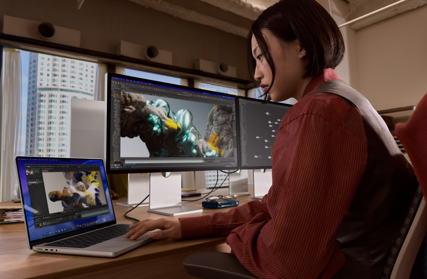 一個人在辦公室的場景中使用 MacBook 筆電進行工作，筆電是透過 Thunderbolt 5 埠連接至 Studio Display XDR